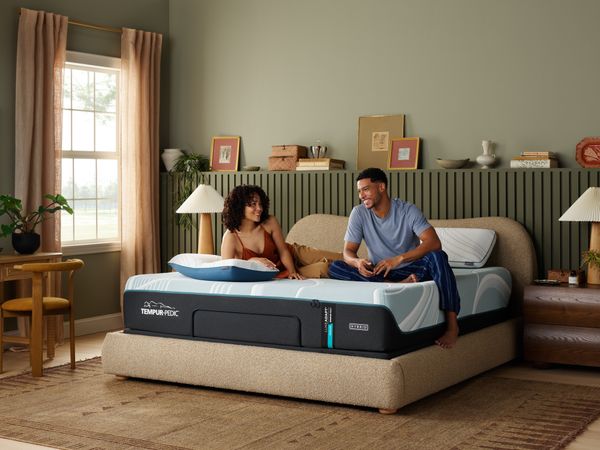 A couple smiling on a Tempur-Pedic mattress 
