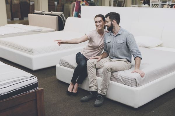 A man and a woman smiling atop a mattress