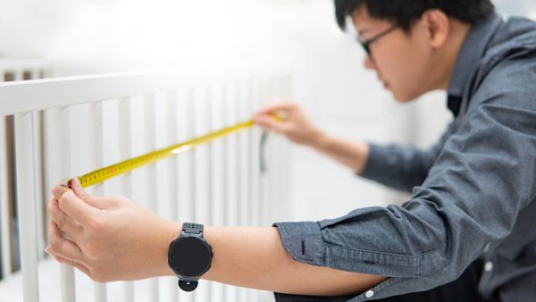A man measuring a slatted headboard 