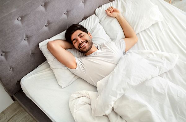 A smiling man sleeping on his back 