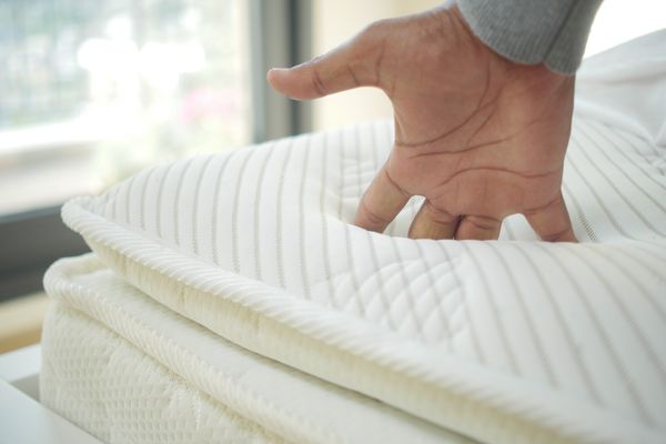 A person sinking their hand into a mattress 
