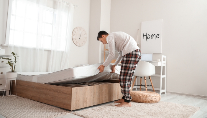 Man rotating mattress on the bed frame