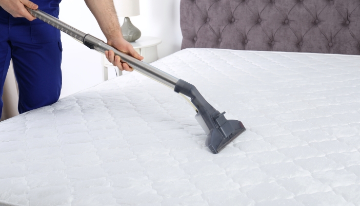 Closeup of someone vacuuming a mattress