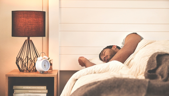 Man sleeping with a nightstand full of books next to him
