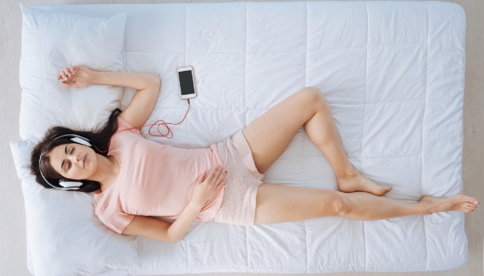 Woman sleeping on a comfortable mattress with headphones