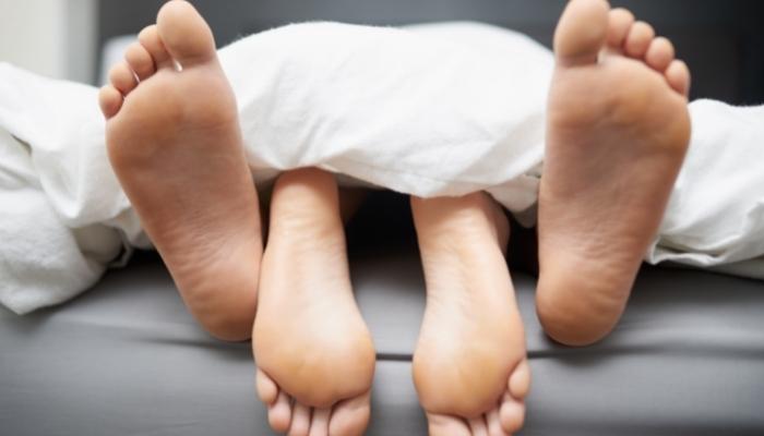 Couple’s bare feet peeking out underneath the covers