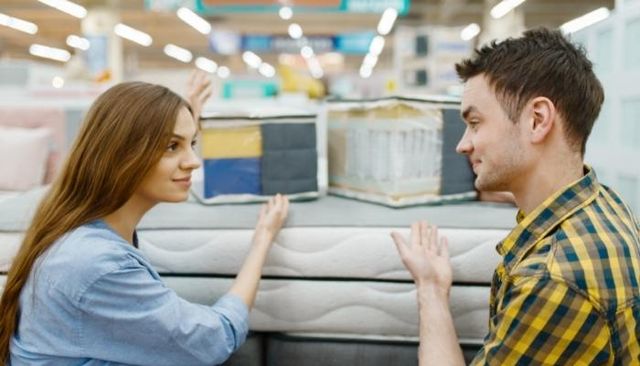 view of a man and woman examining different types of hybrid mattresses