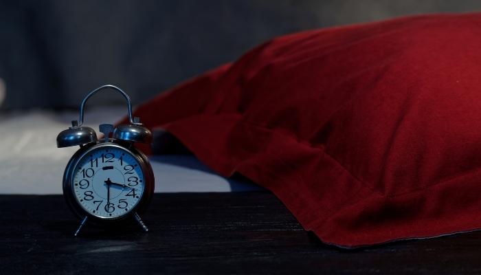 Red pillow with old clock next to it 