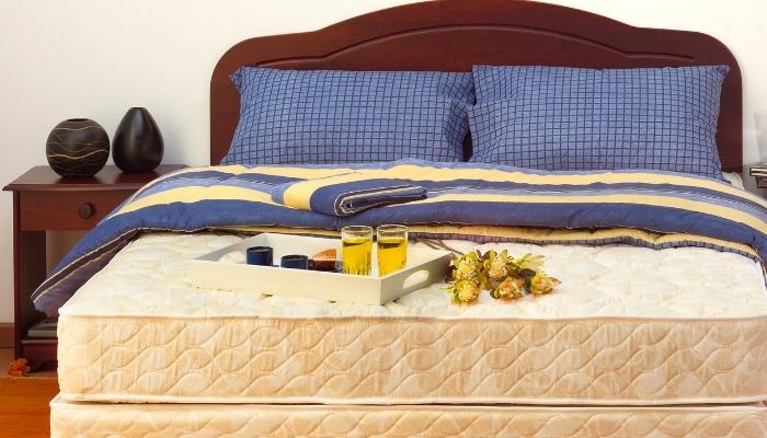 Bed with covers turned back and tray with drinks and flowers next to it