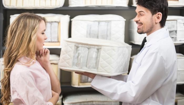 Two people looking at a mattress cutout to look at the springs