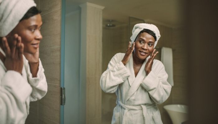 woman smiling into mirror touching face