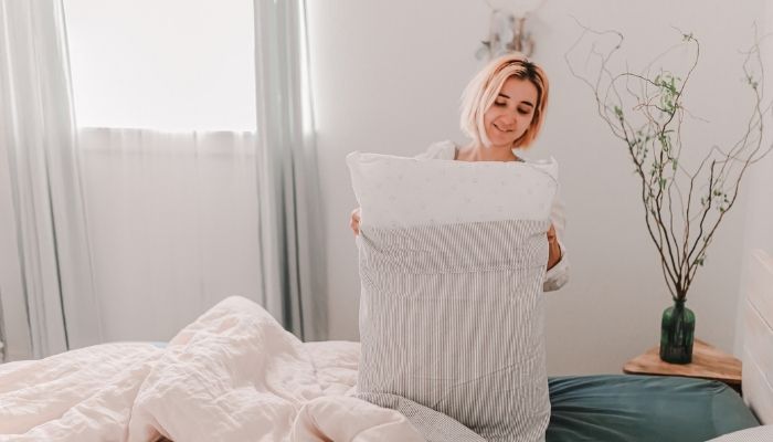 woman changing bed sheets and pillowcases