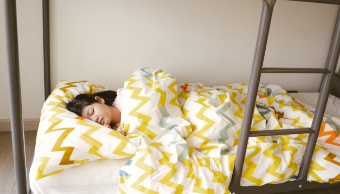 Child sleeping on their side in the bottom bunk
