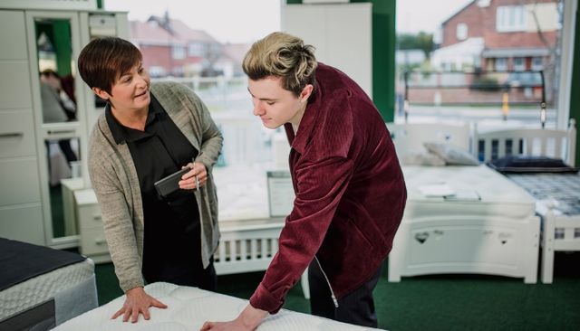 mattress-shopping front view of a person in a mattress store discussing a mattress with a store associate