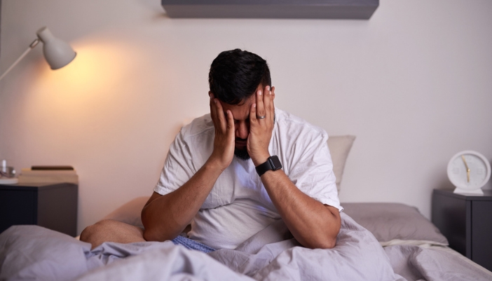 A man struggles to sleep in bed at night.