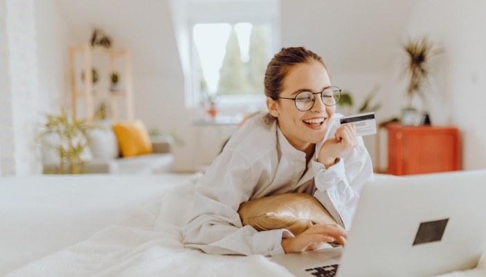 A woman shops online from her bedroom at home.