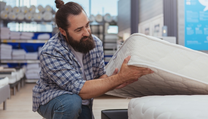 A man shops for a mattress in a showroom.