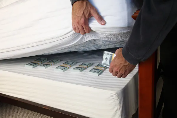 front view of a man placing money under a mattress