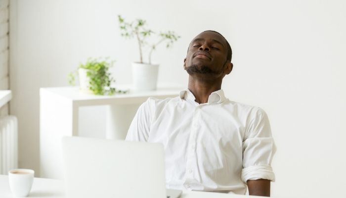 man with eyes closed sitting at work desk