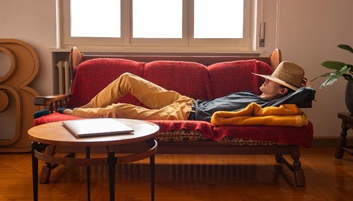 Man in straw hat is taking a siesta on the couch