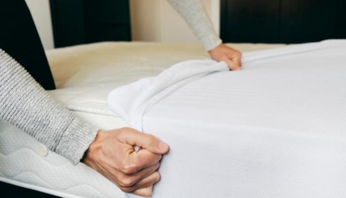 Hands putting a mattress protector on