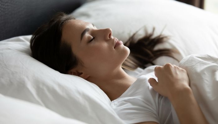 young woman lying on back on comfy bed