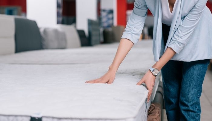 view of woman touching orthopedic mattress in furniture shop