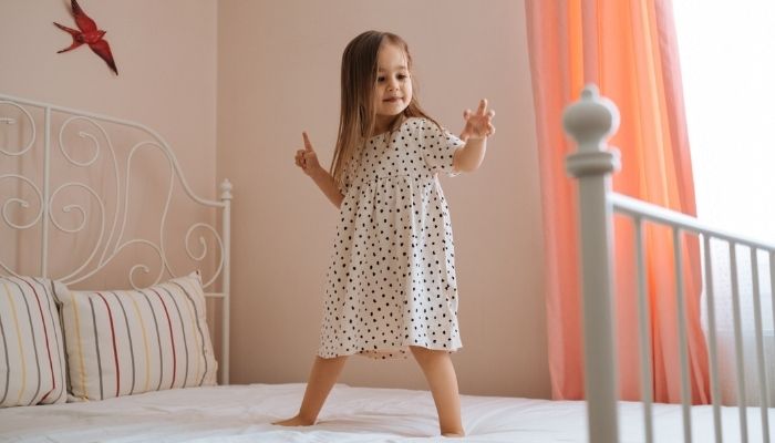 Young girl standing on her bed