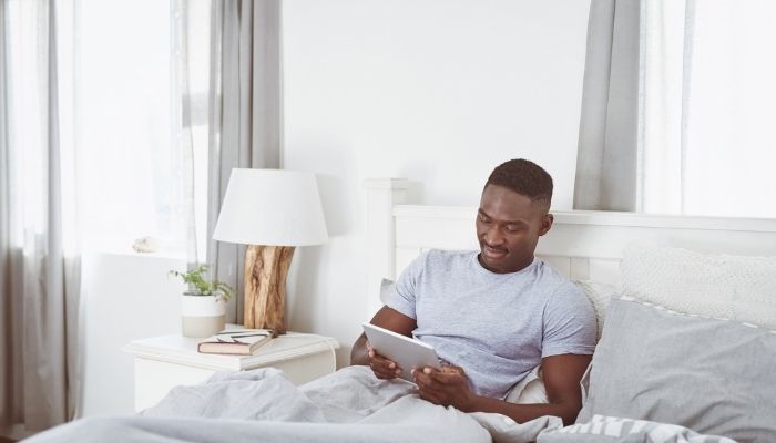 man in bed looking at tablet 