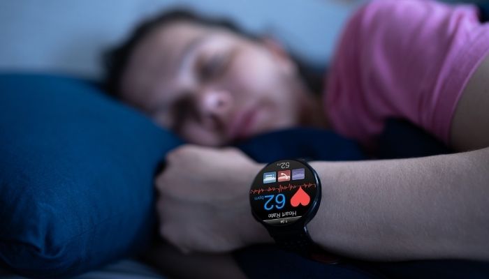 woman wearing sleep tracker watch in bed 