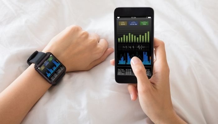 close-up of hand with smartwatch and phone showing health data