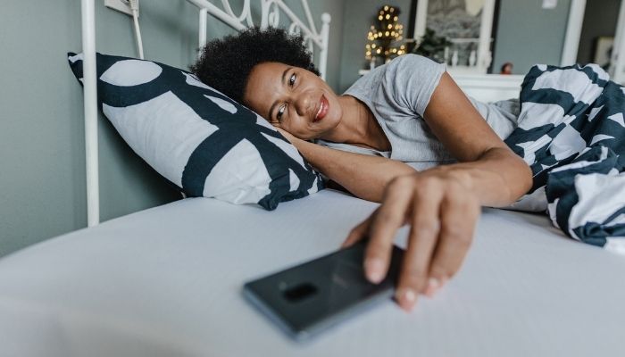 woman waking up to grab smart phone