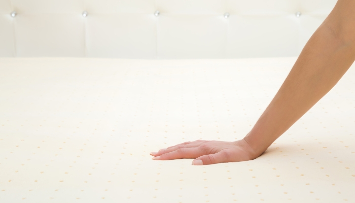Hand testing out the material of a mattress