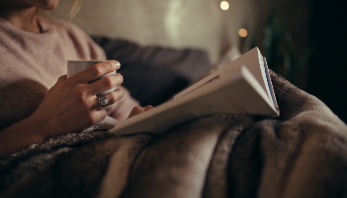 Closeup of someone reading a book in a darkened corner before bed
