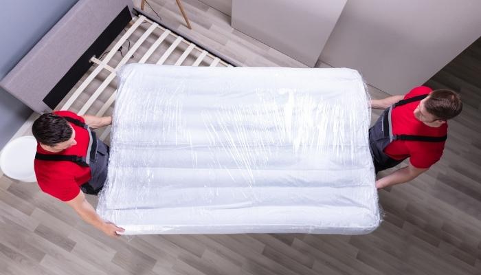 Two delivery men installing new mattress