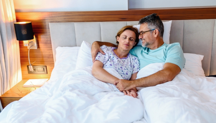 Couple laying down in bed, getting ready for sleep