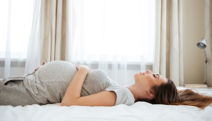 An expectant mom lying on her back and sleeping peacefully