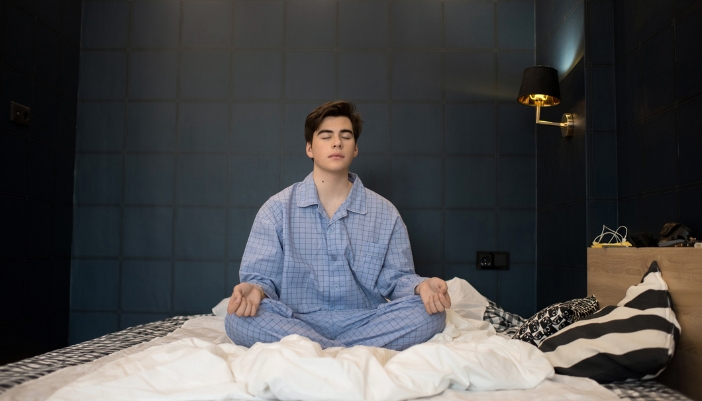 Man meditating in bed to calm his mind before sleeping