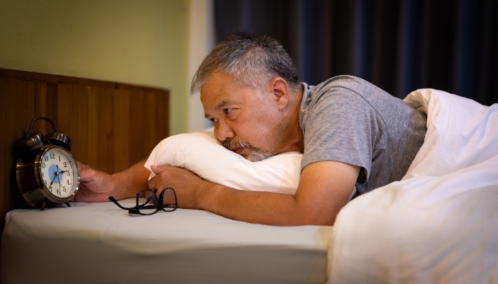 Older man staring at the clock after being woken up