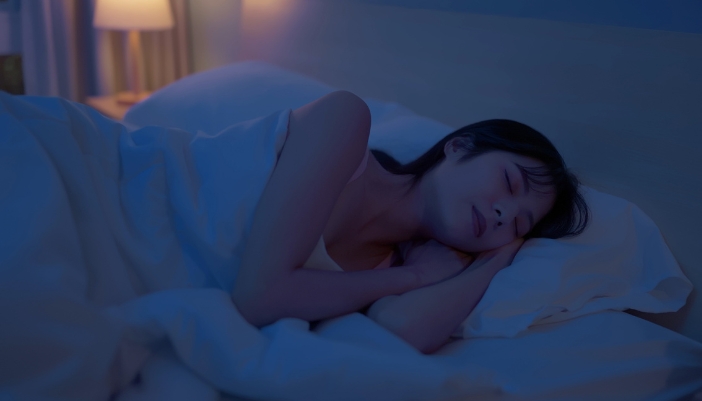 Woman deep asleep with a soft lamp next to her bed