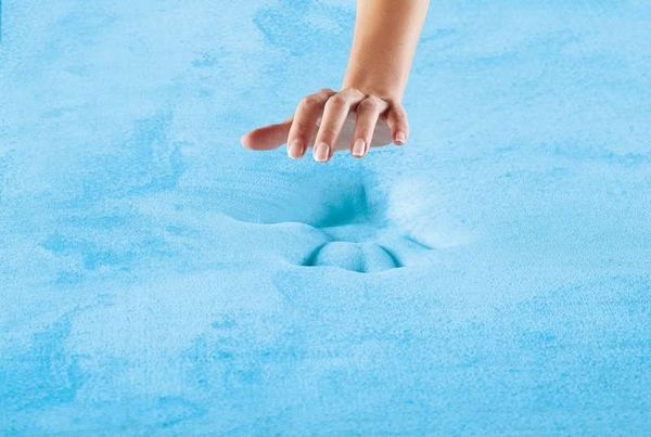 A person pressing onto a gel memory foam mattress