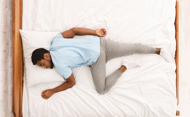 Front view of a man sleeping on his stomach on a mattress