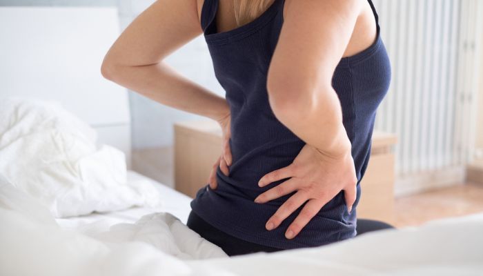 woman waking up in the morning rubbing back