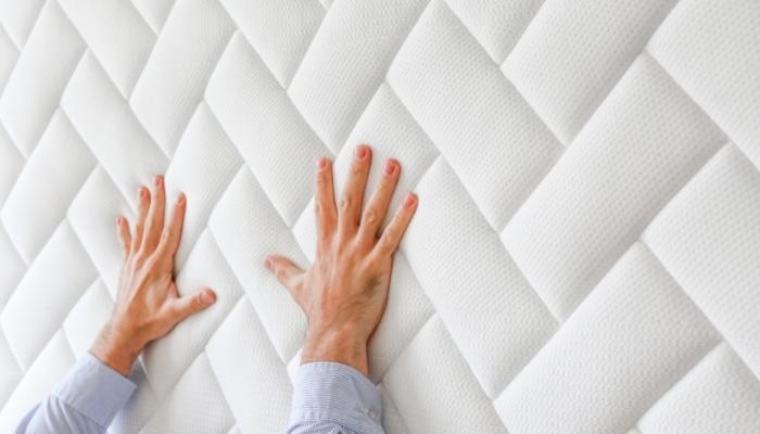 Hands testing the feel of a new mattress