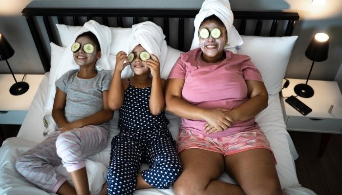 mother and daughters in bed doing skin care.