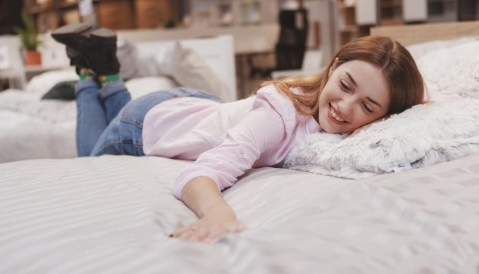 female customer trying new bed at furniture store