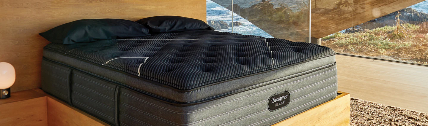 A Beautyrest Black pillow top mattress rests atop a wood bed frame