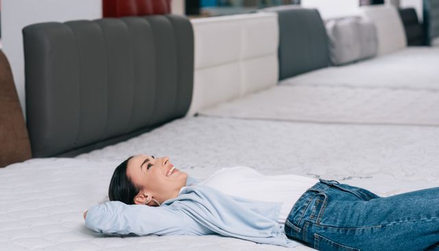front view of a woman laying on a medium firm mattress in a mattress store