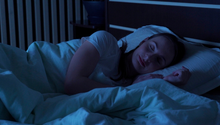 Woman sleeping in a comfortable, cool, and dark room