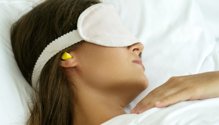 Woman sleeping with a face mask and earplugs
